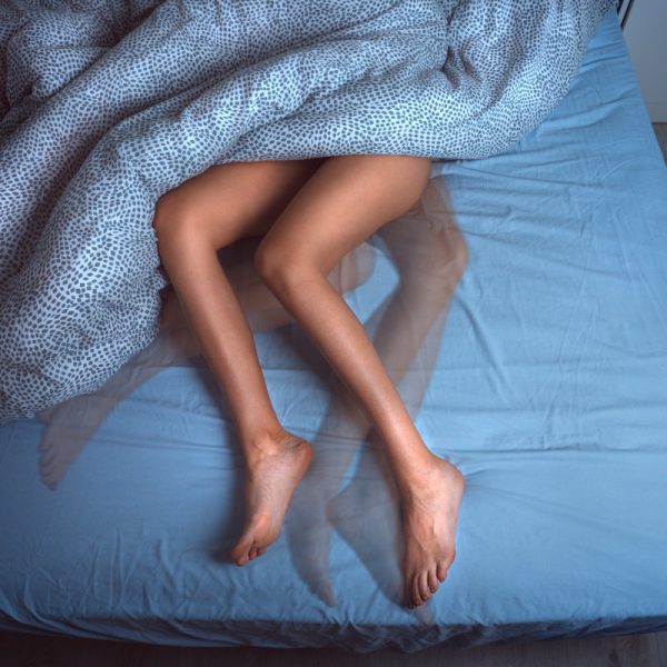 Woman sleeping in the bed and suffering from RLS or restless legs syndrome. High quality photo